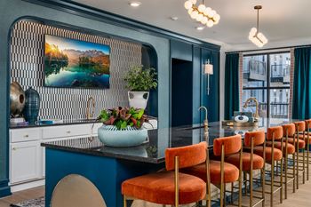 a dining room with blue walls and a bar with orange chairs